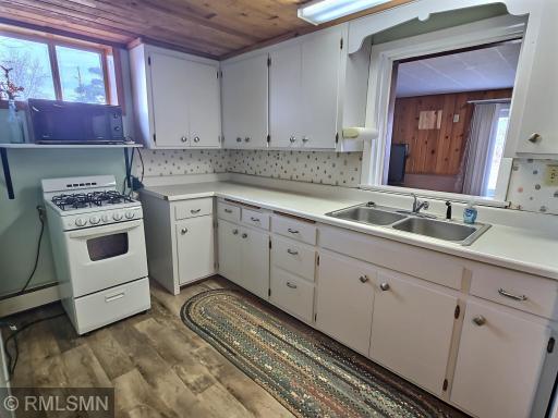 Knotty pine ceilings, LVP flooring, and white cabinets make this space charming and practical.