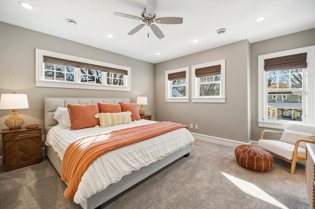 Windows wrap the primary bedroom in natural light, creating a soft, welcoming atmosphere from morning through evening.