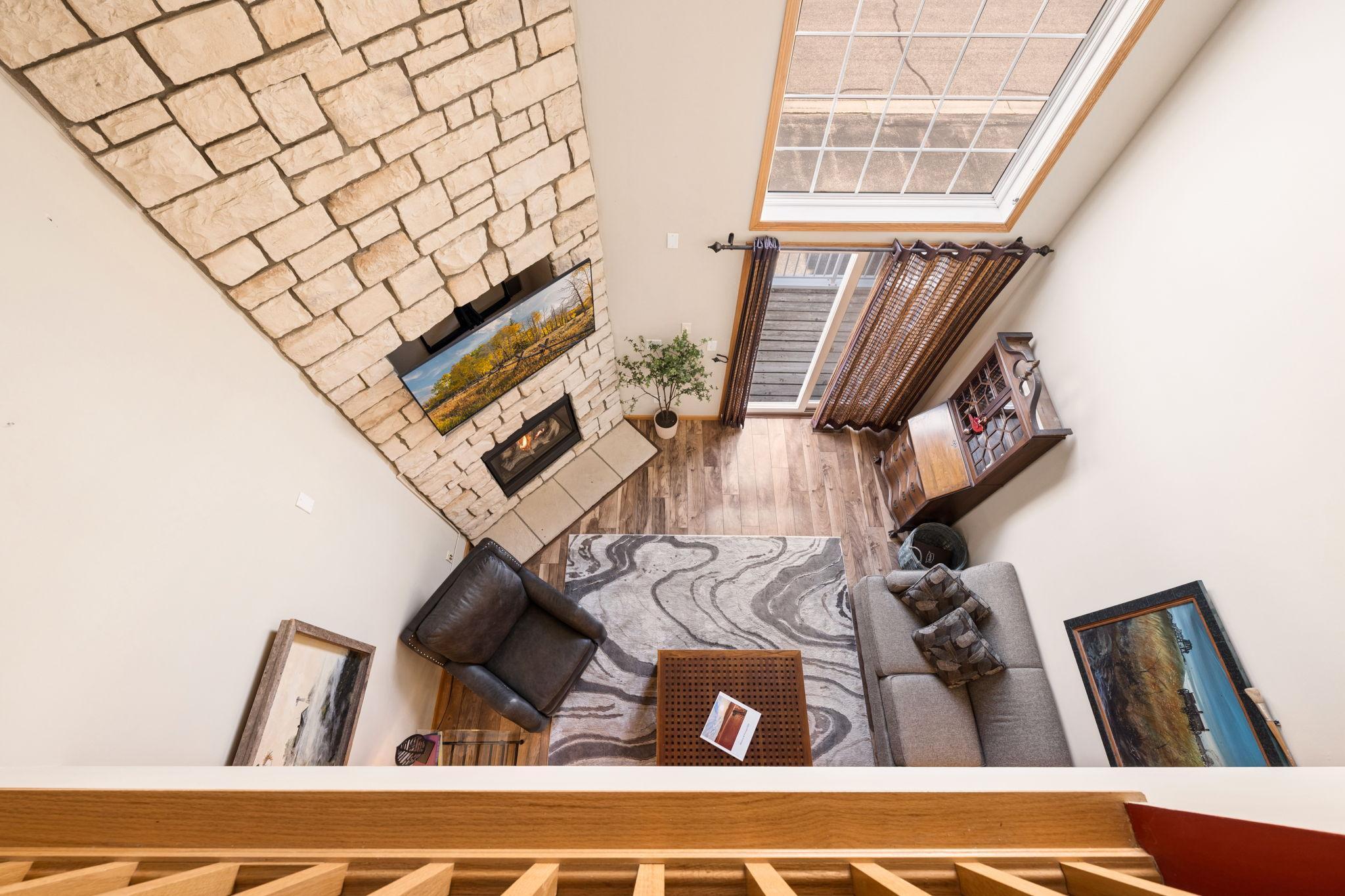 A stunning open-to-below design brings in natural light and highlights the floor-to-ceiling stone fireplace—creating a true focal point from every level.