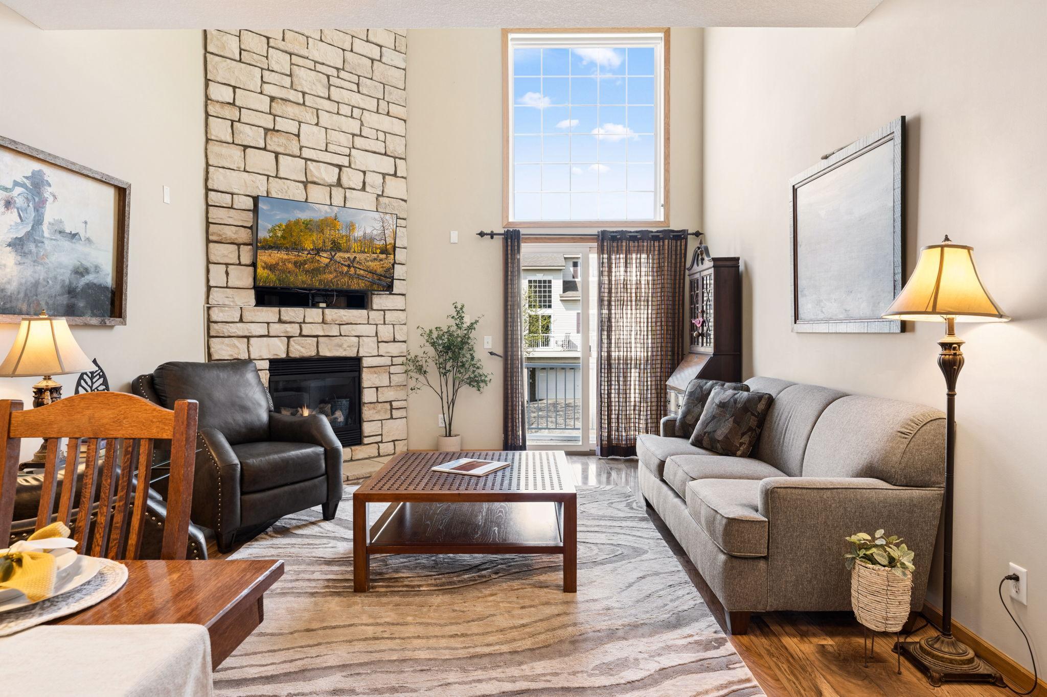 Inviting living room centered around a beautiful stone fireplace and soaring ceilings. Large windows and deck access enhance light and livability.