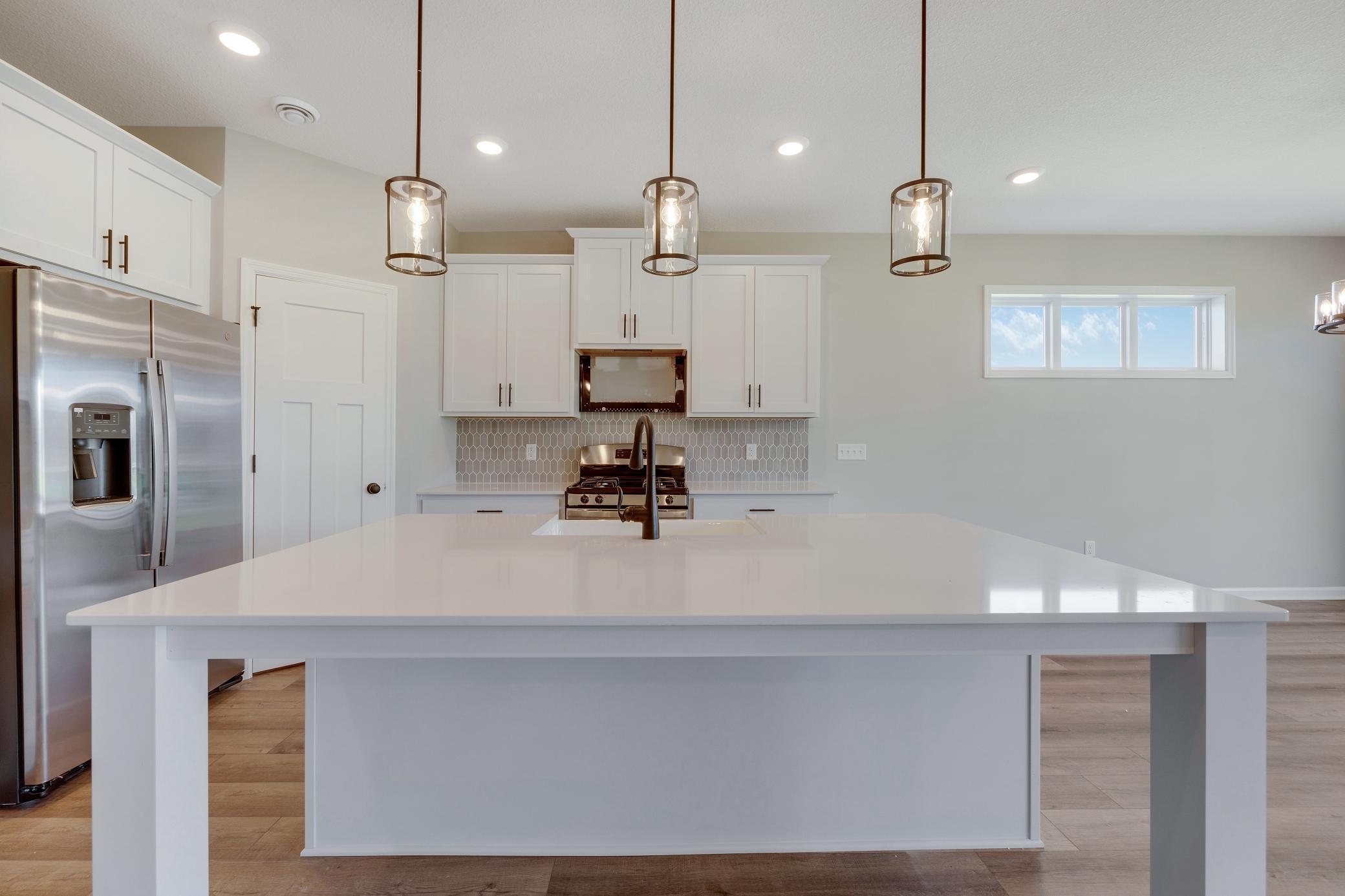 Large island with plenty of seating. Photo of similar home. Not actual home. Styles and finishes will vary.