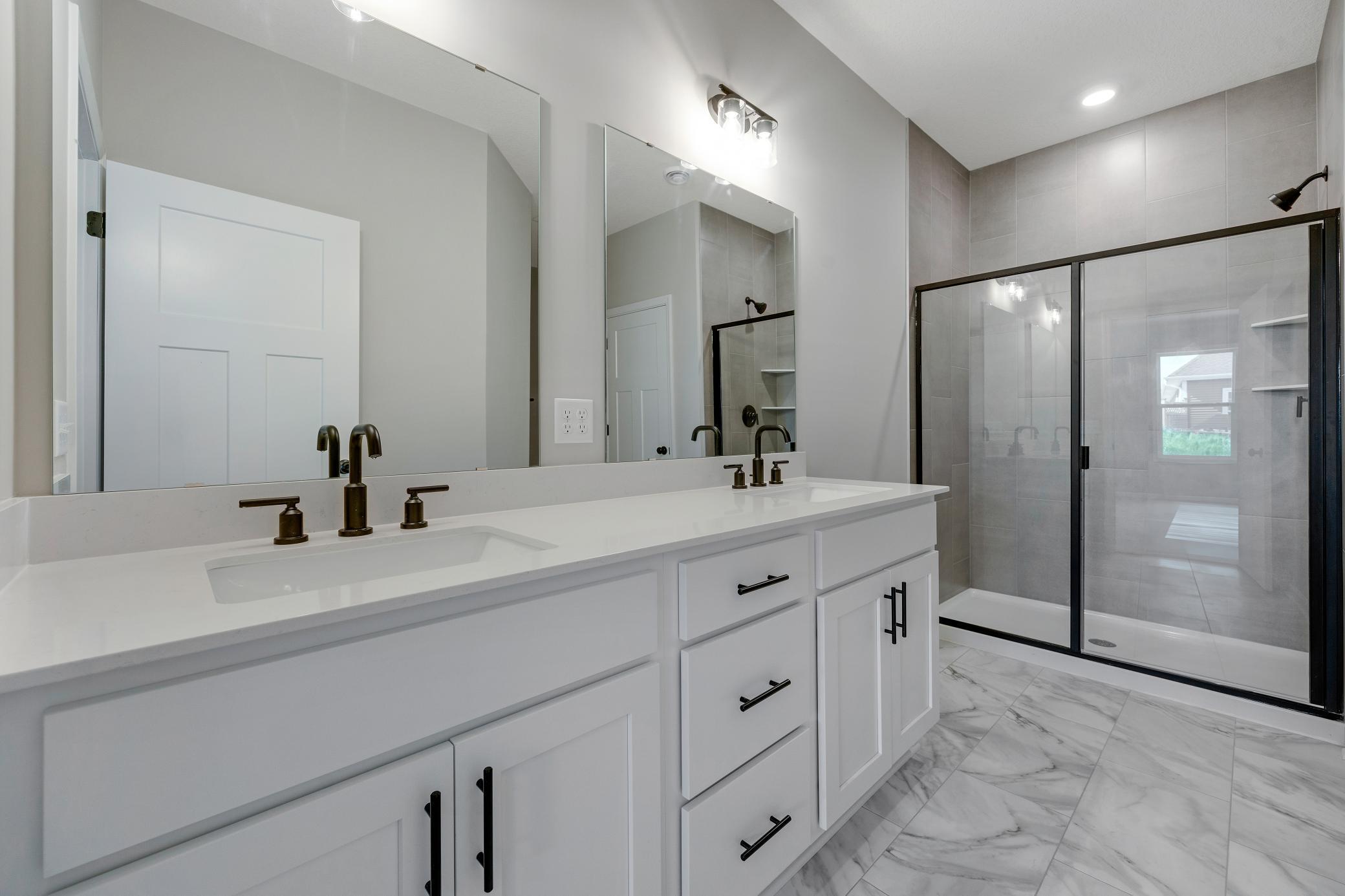 Owner's bathroom with dual vanities. Photo of similar home. Not actual home. Styles and finishes will vary.