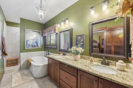 The stunning primary bath offers tile floors, double sinks with granite countertops, a standalone soaking tub, and a tile-surround walk-in shower.