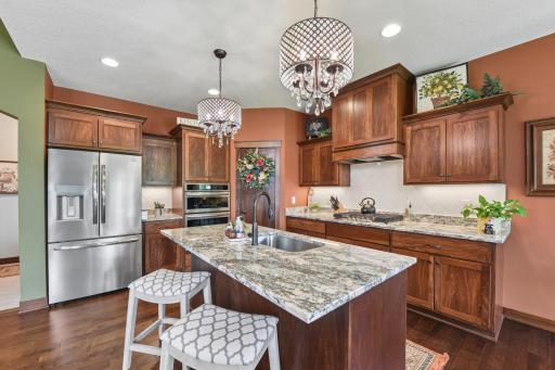 The gourmet kitchen offers upgraded stainless appliances, beautiful granite tops, custom cabinets, tile backsplash, kitchen island, and walk-in pantry.