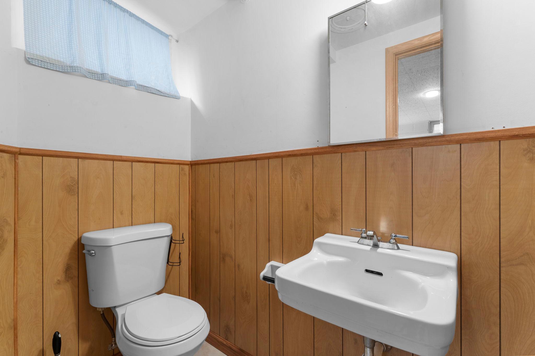 A finished private powder room is accented by wood panel wainscoting. The laundry area is equipped with a utility sink and cabinetry for everyday convenience, while the remainder provides excellent potential for future finishing.