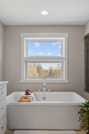 Soaking tub perfectly positioned beneath the window, creating a peaceful, spa-like retreat with natural light and views.