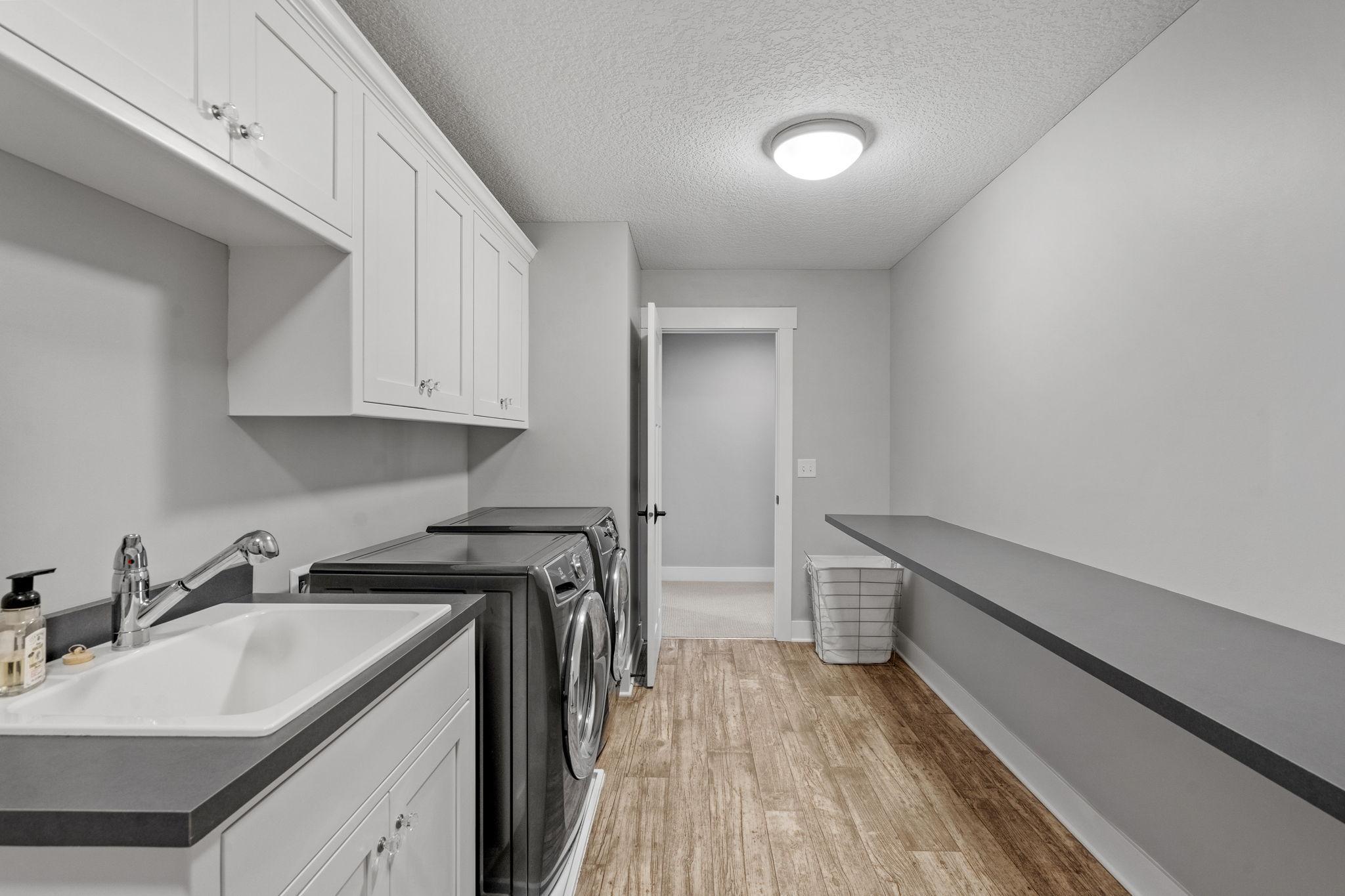 Convenient second-floor laundry with built-in cabinetry, utility sink, and a long folding counter for everyday ease.