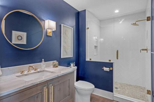 Dark, moody, and done right. This lower level bath brings bold design with rich navy walls, warm brass finishes, and a clean, modern feel.