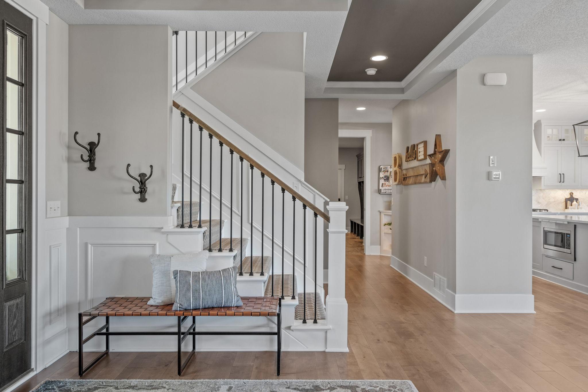 Thoughtfully designed entry with clean lines, warm wood accents, and a staircase that blends classic detail with modern style.