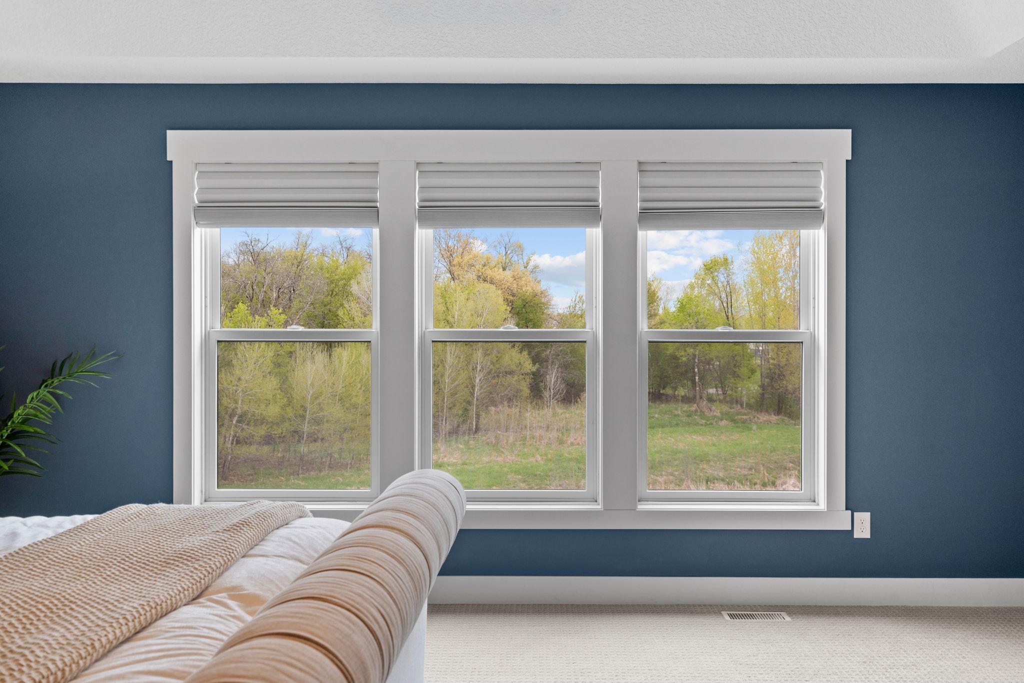 Serene retreat with oversized windows bringing in natural light and peaceful backyard views.