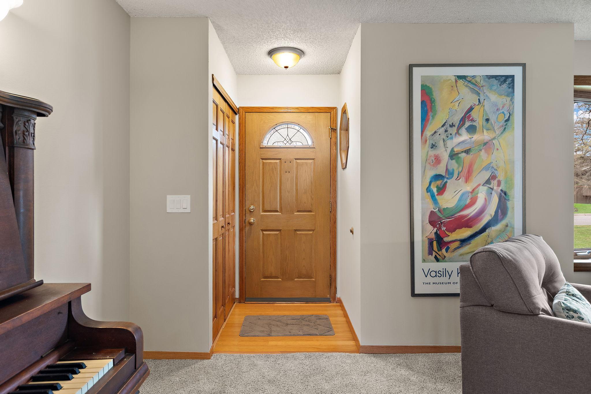 The front entrance of the home with coat closets to the left and small octagon window to the right. The sellers are willing to leave the upright piano if a buyer would like it to stay with the home.