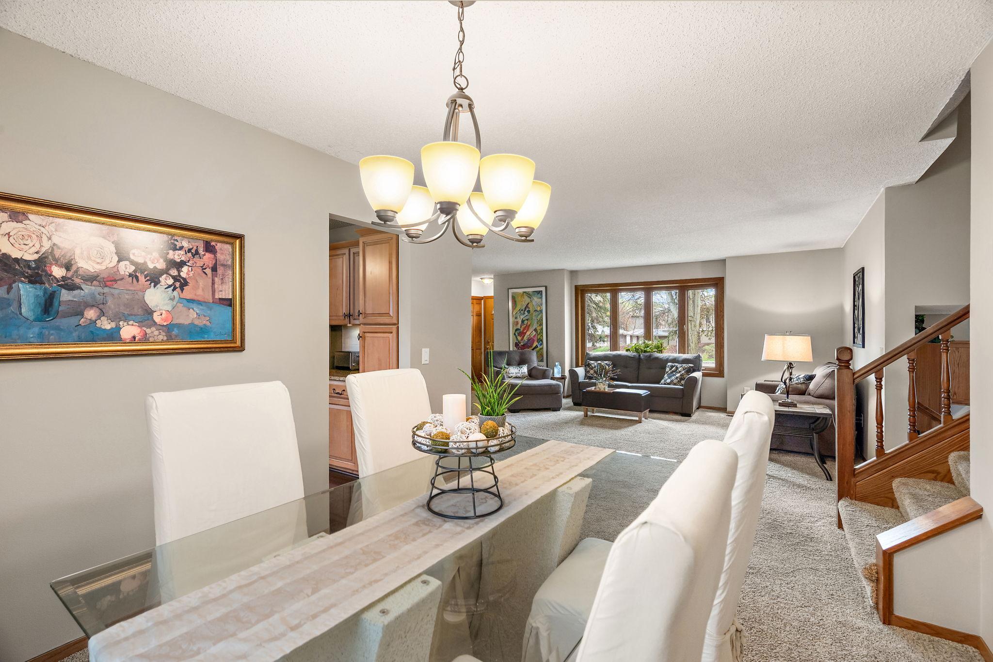 Standing in the formal dining room and looking to the living room beyond with kitchen on the left and upper level staircase on the right.