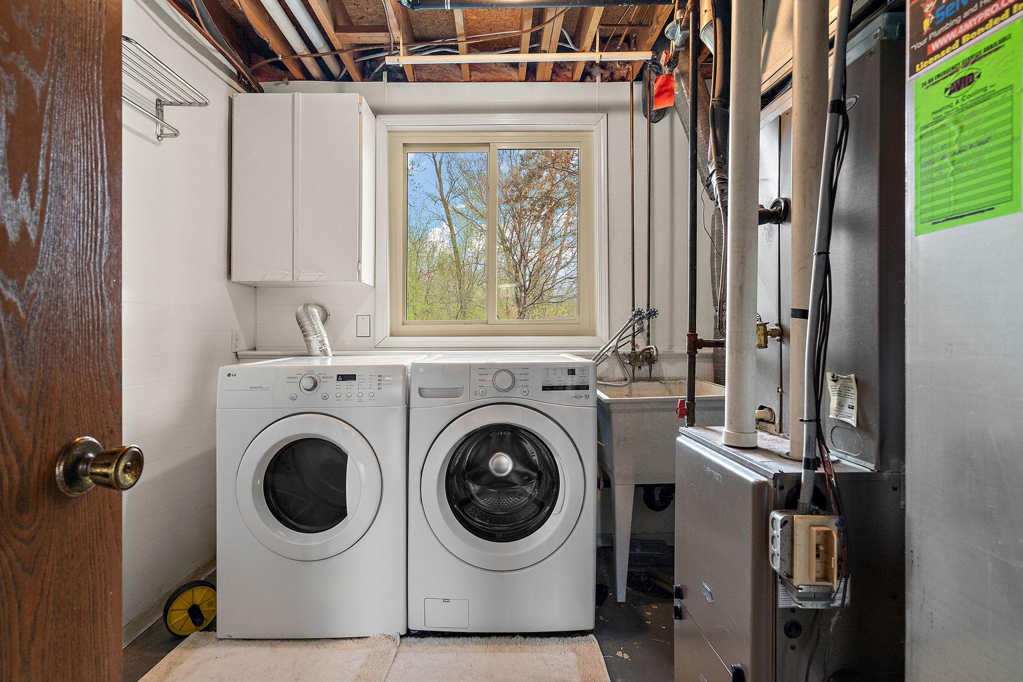 Lower level utility room with dryer and a 2025 washer. There is also a convenient laundry sink and a window to allow natural light in.