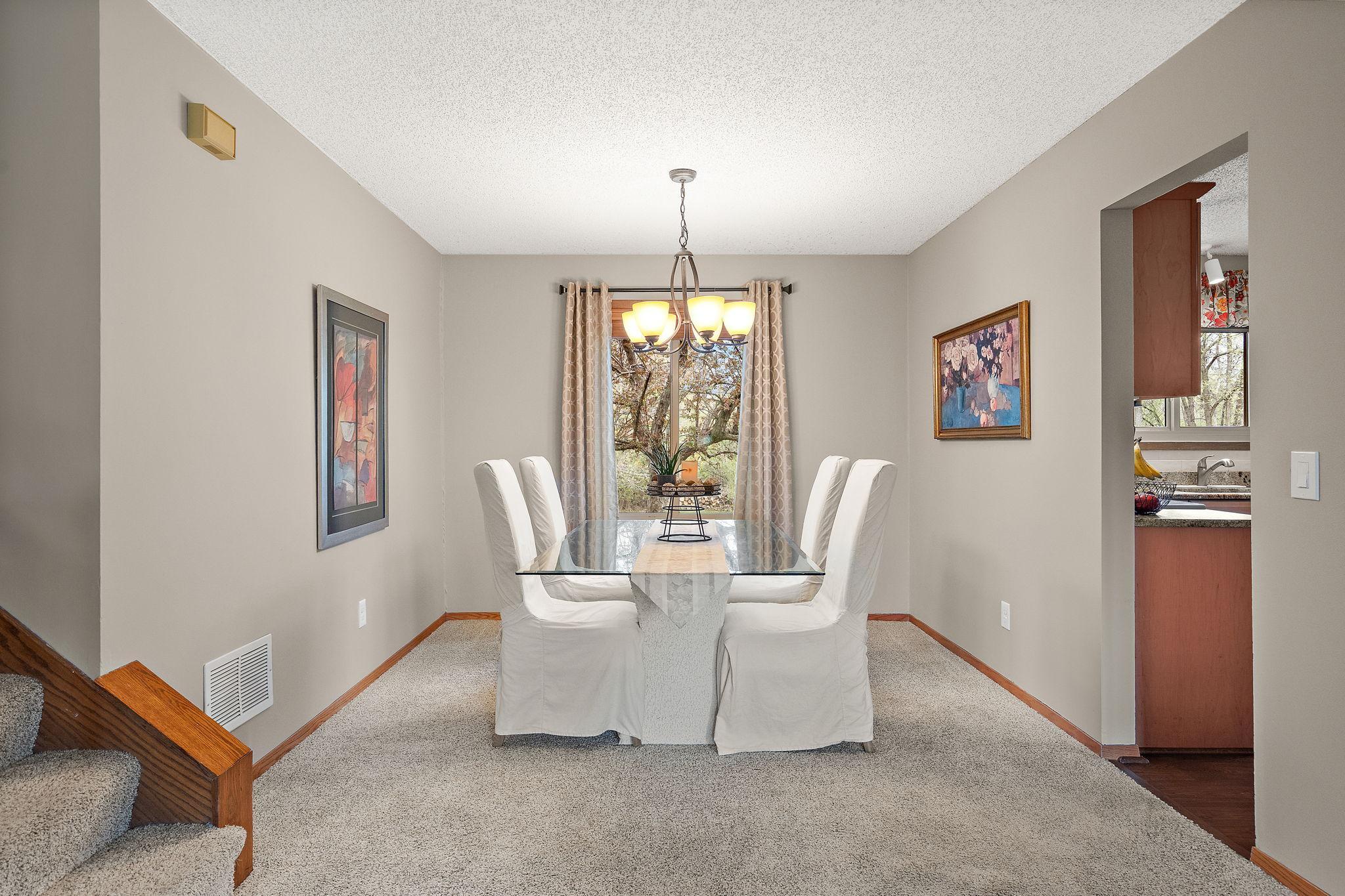 The formal dining room is right off the kitchen and near the stairs leading to the upper level and features a warm, modern light fixture and window for additional light with a view of the backyard.