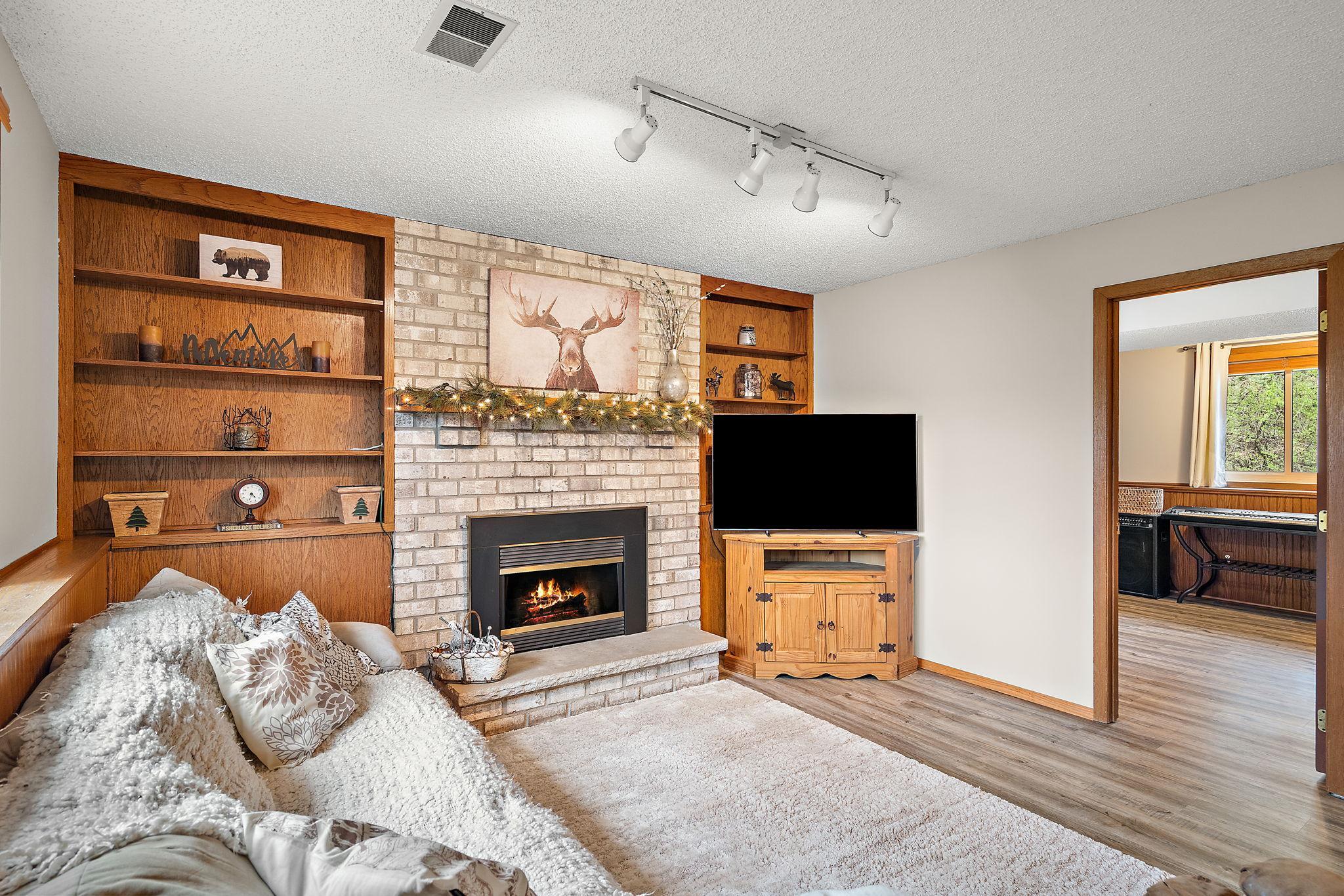 The lower level recreation room features built in shelves for a family library or media collection with the lower level fourth bedroom through the door on the right.