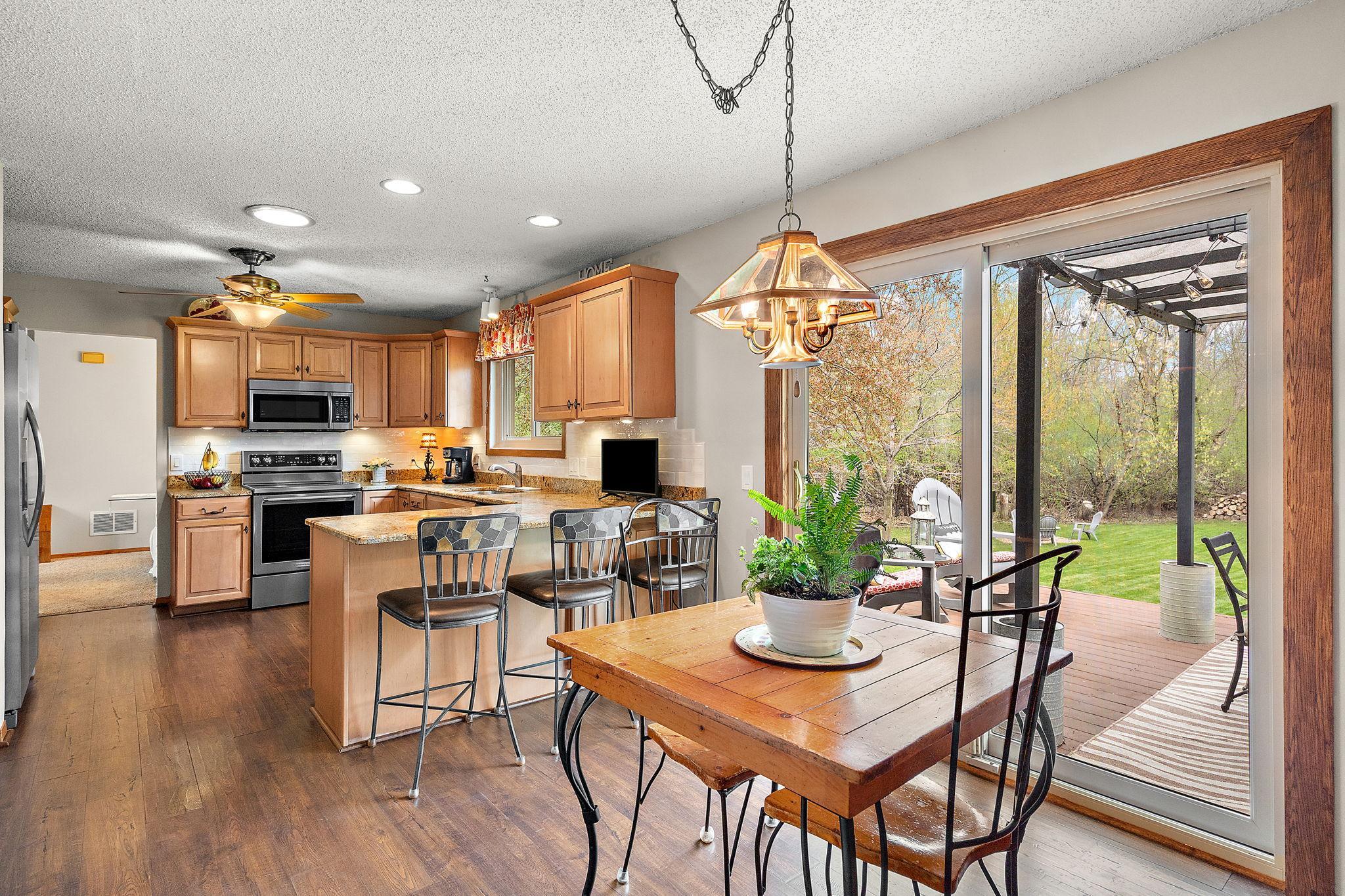 Standing in the dining area facing the kitchen with a view of the backyard through the deck patio doors on the right.