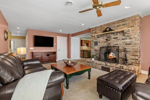 That floor-to-ceiling brick fireplace isn't just a focal point, it's the soul of this home on a cold Minnesota night. Crackling wood, leather sofas, and the warm amber glow of a fire that's been lighting this room for decades.