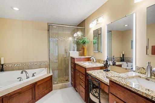 Remodeled in 2016, the primary bedroom has tile floors, double sinks, a make-up area with a lighted mirror, a walk-in tile surround shower and separate jetted tub.