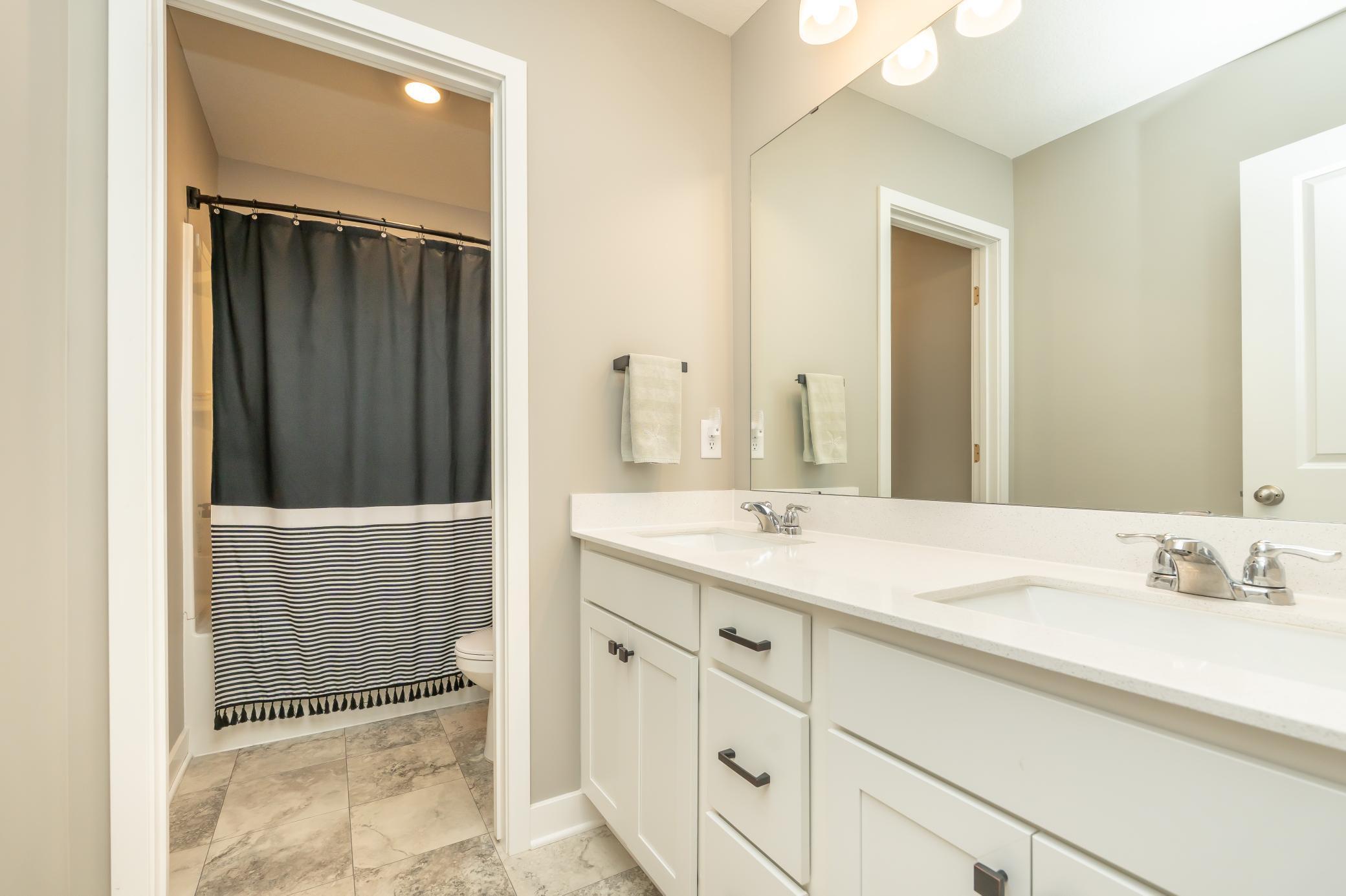 Upper level full bathroom with duel sinks, tub and toilet closet as well