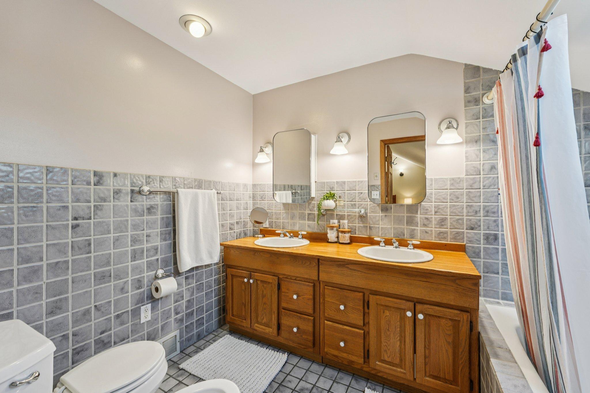 Spacious upper level bathroom with double vanity and classic tile detail.