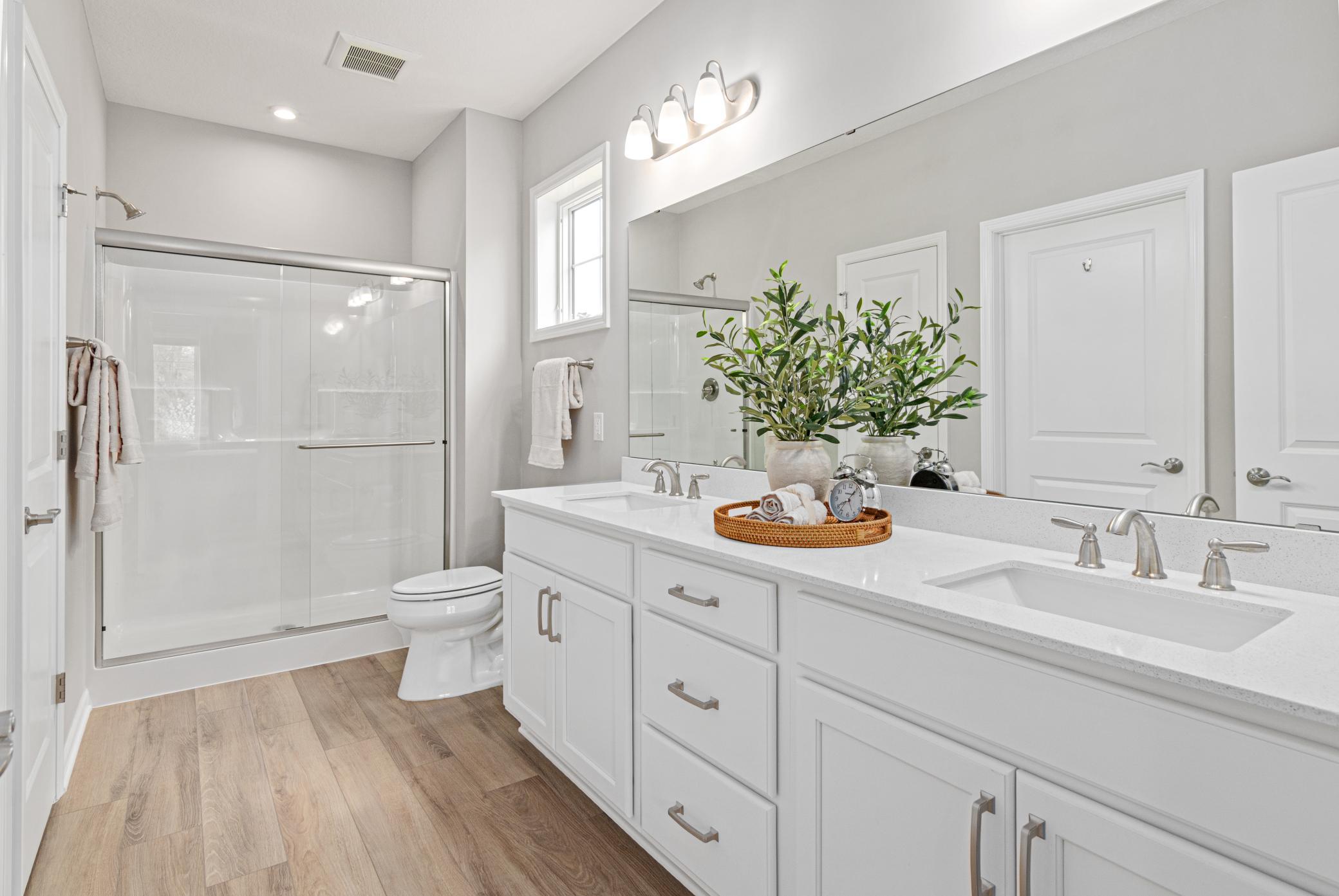 Primary private bath with a double vanity, walk-in shower and an extended walk-in closet.