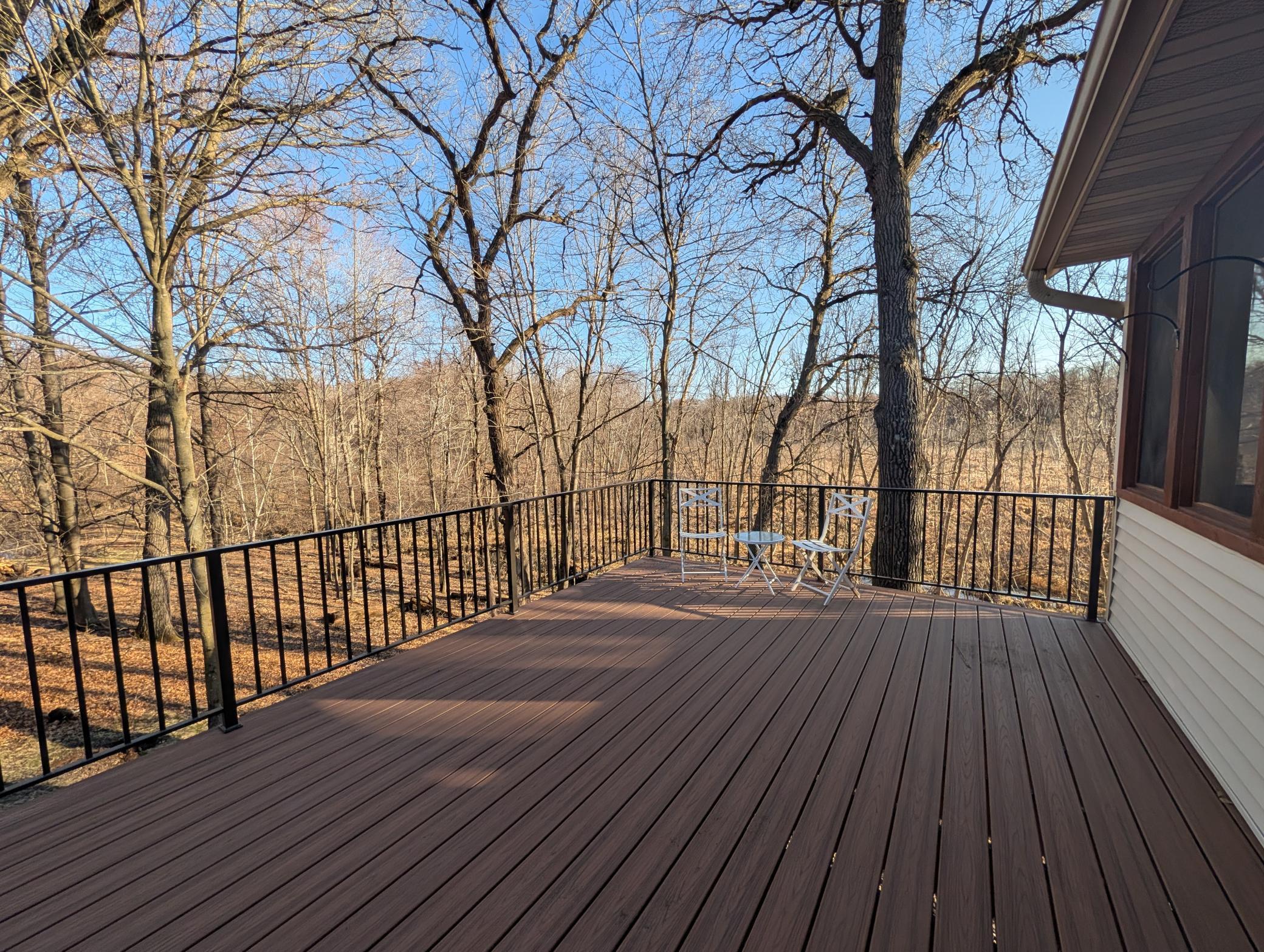 Large deck off of screen porch and primary bedroom with brand new flooring and railing to enjoy the natural setting of this home