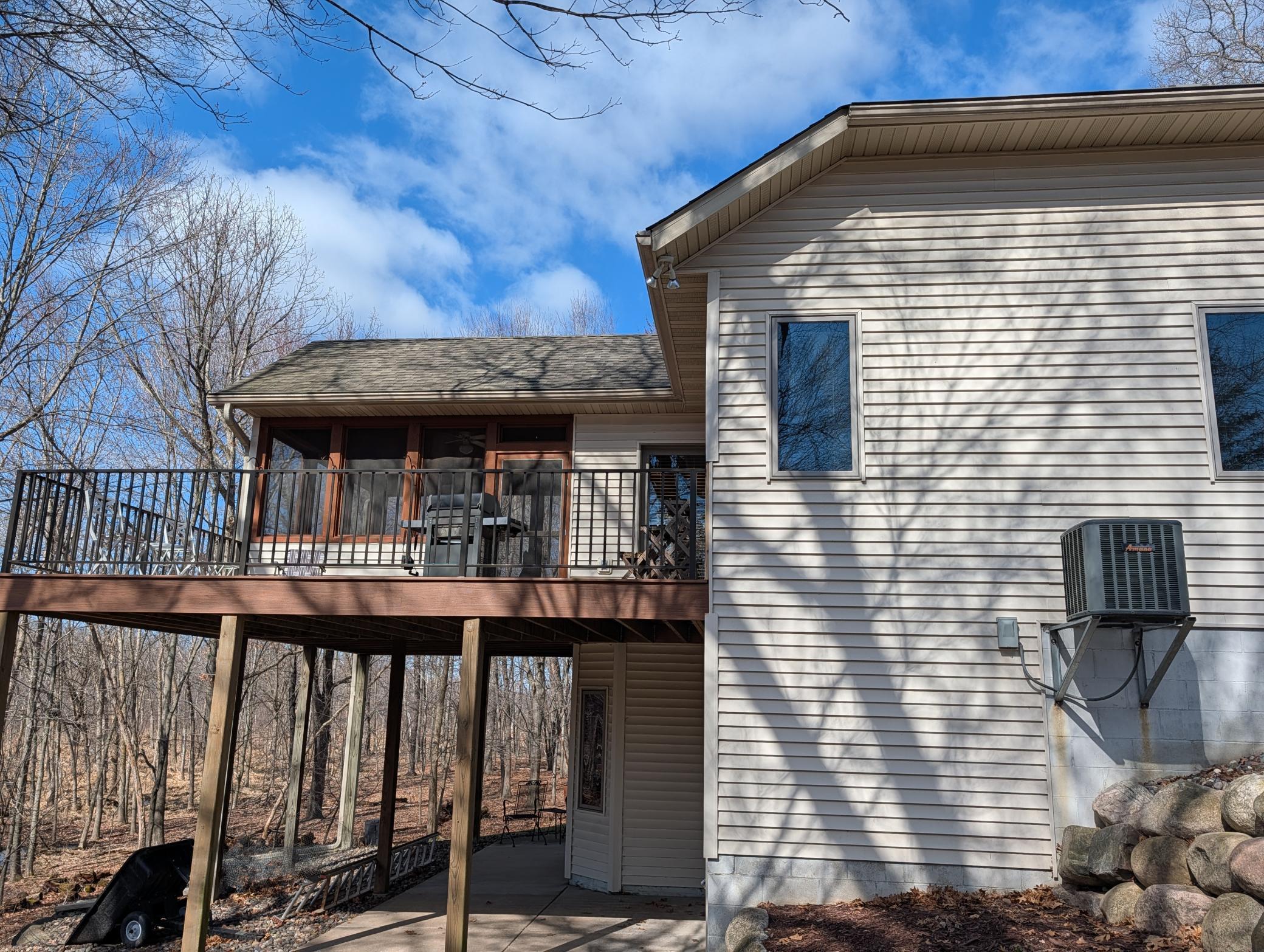 Walkout from lower level to concrete patio with deck and 3 season porch above