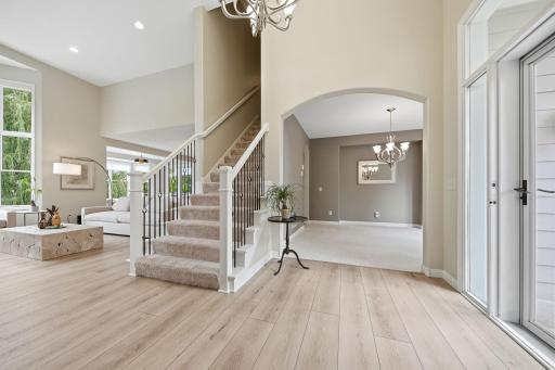 An expansive, wow foyer featuring a stately front door with side gable surround windows and beautiful transom window