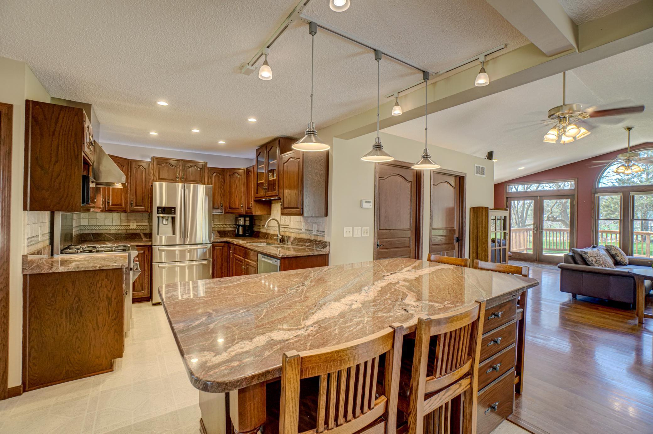 The kitchen is designed to impress and perform, featuring a large center island, granite countertops, stainless steel appliances including a Wolf range, abundant cabinetry, and a cozy breakfast nook.