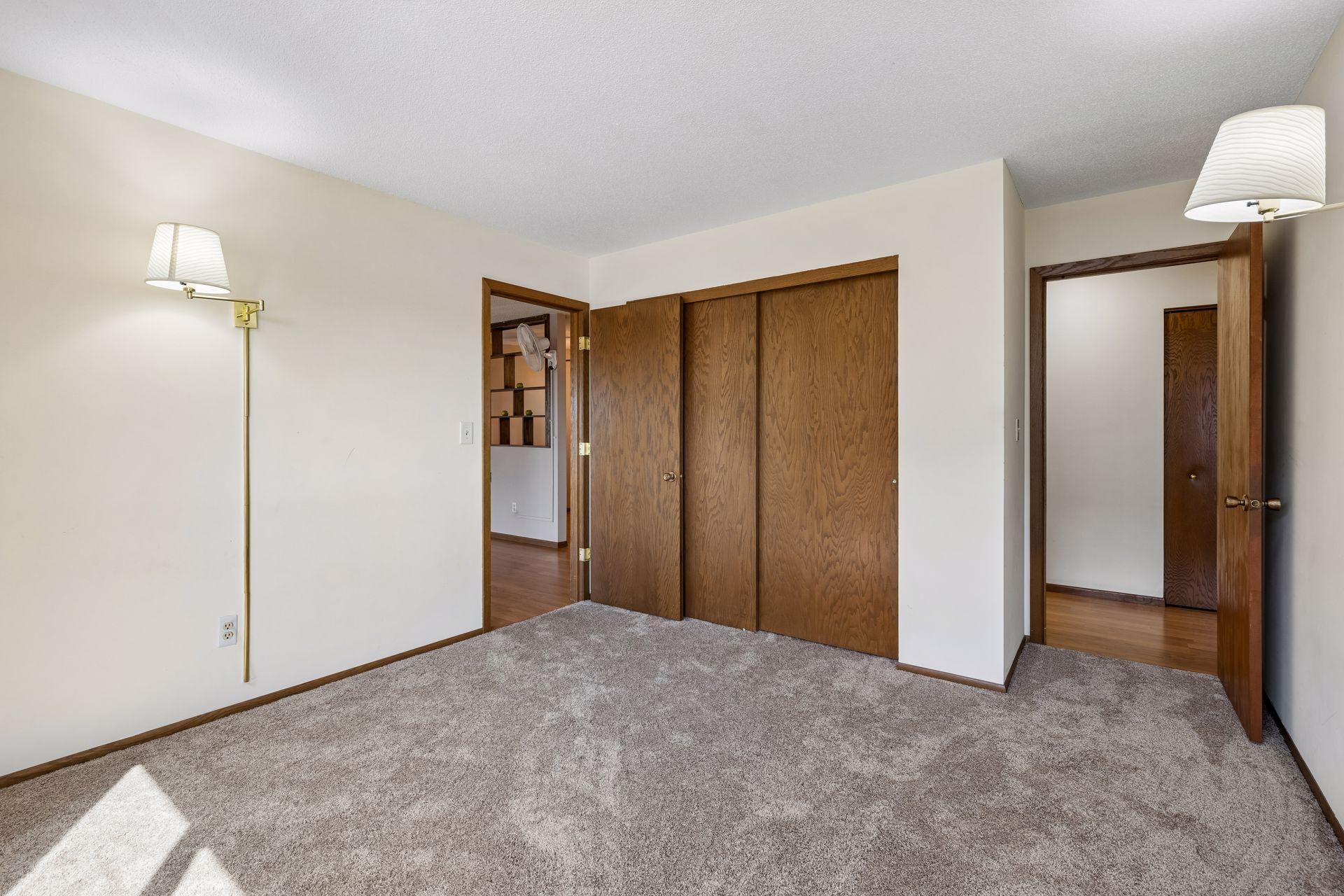 Bedroom one off the living room with view through second door to the hallway and the bathroom.
