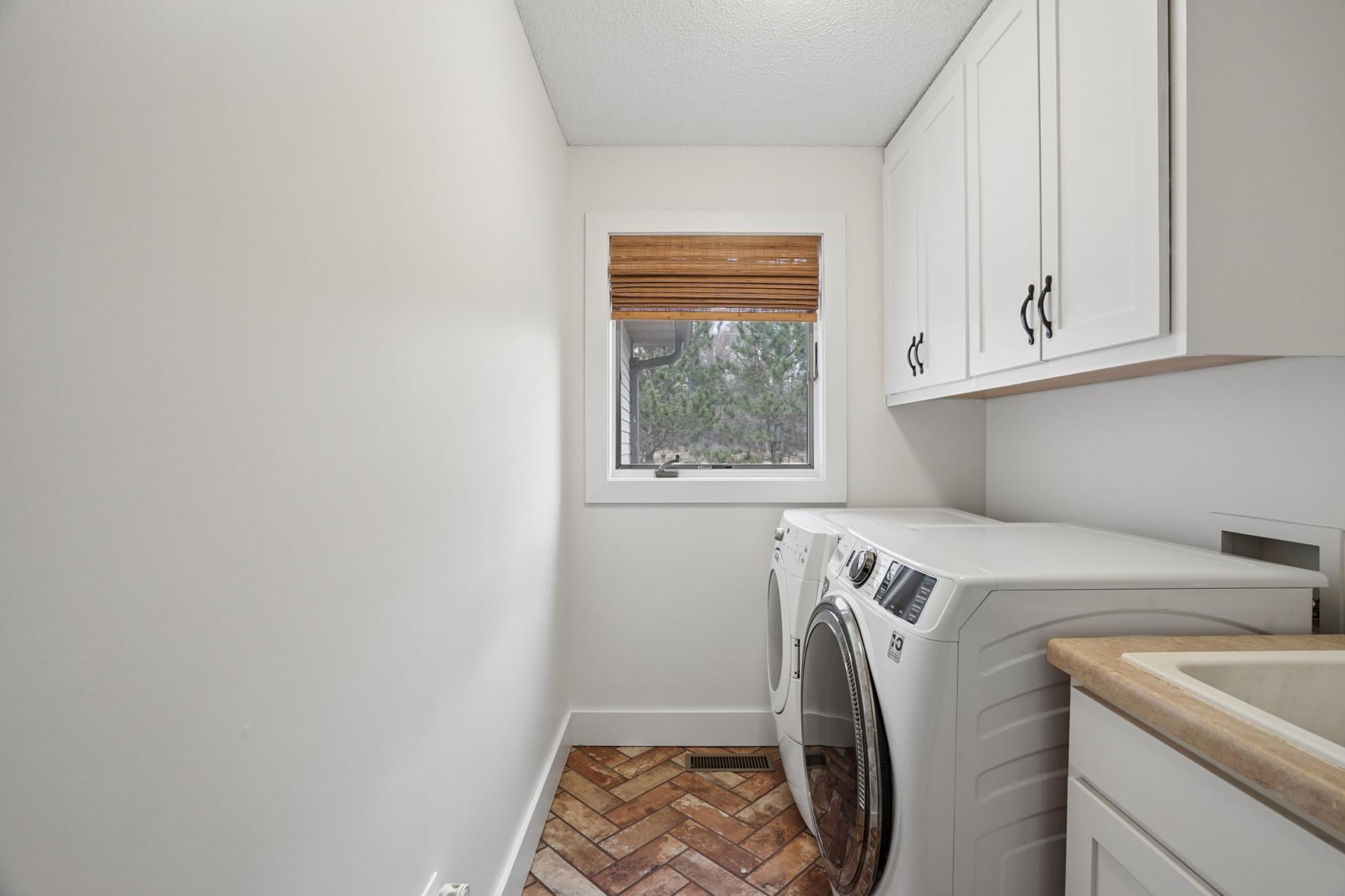 Main floor laundry offers cabinet storage, tile floors, and sink!