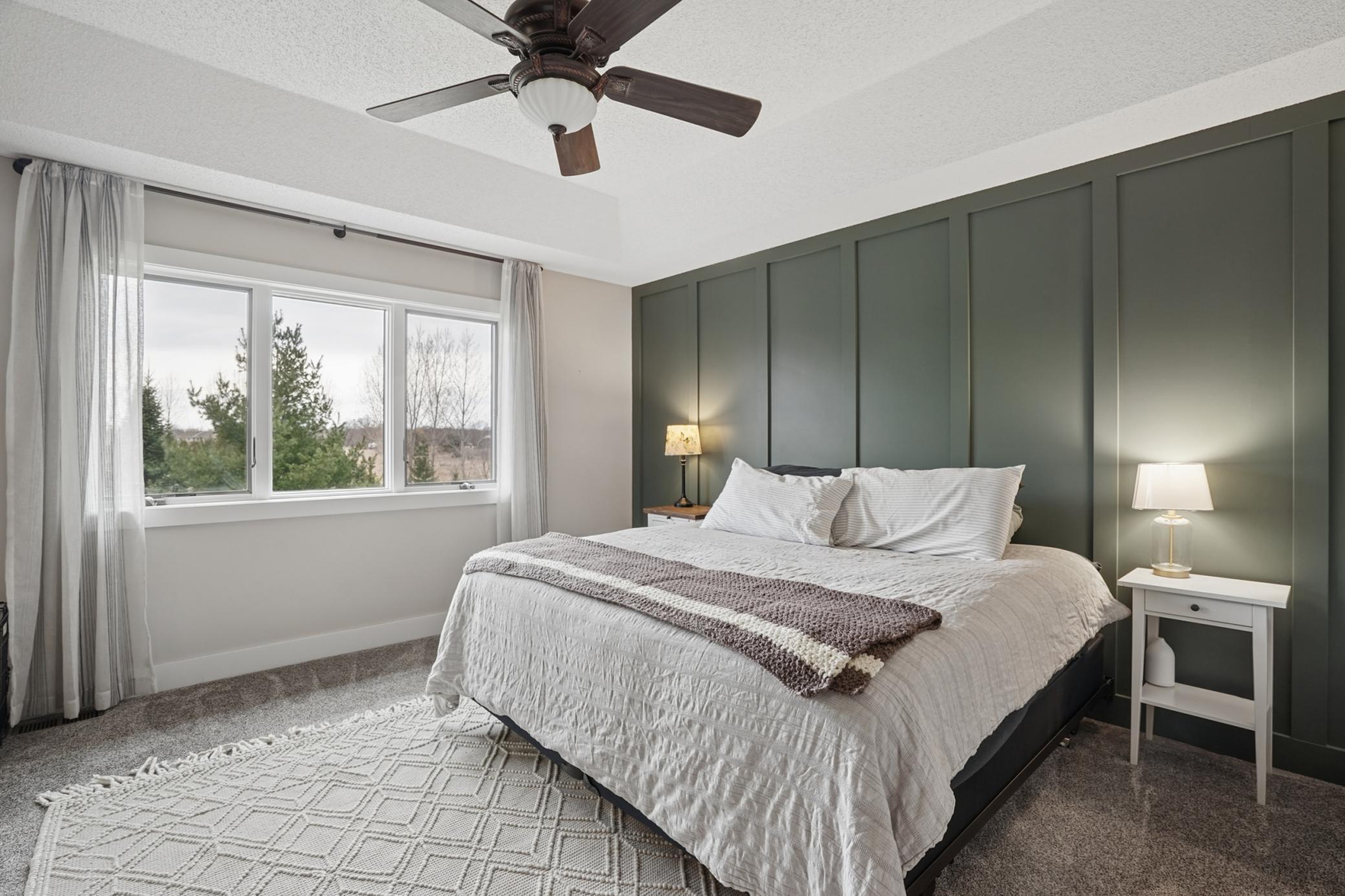 Primary bedroom w/ tray vaulted ceiling, excellent backyard views, and board and batten accent wall!