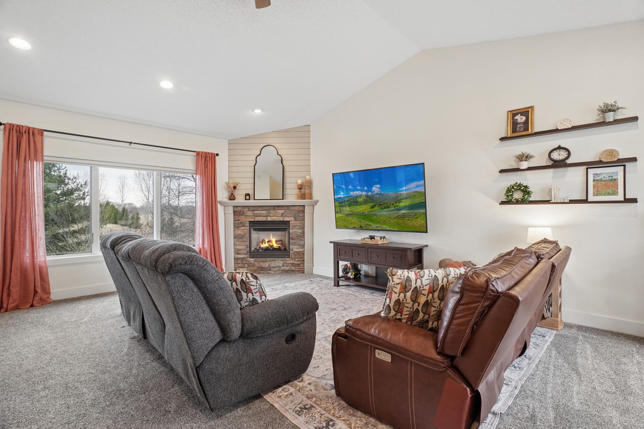 Main floor living area boasts beautiful vaulted ceilings, recessed lighting, gar fireplace with stone and shiplap, and excellent natural lighting