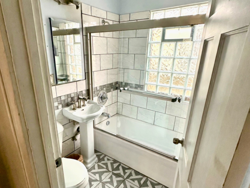 Updated main-level bath featuring tile surround and glass block window for added light and privacy.