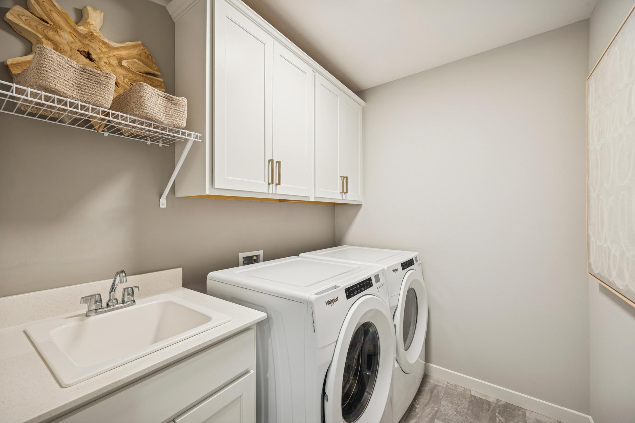 Spacious and well-organized upper-level laundry room designed for everyday ease, featuring ample space for folding, sorting, and storage.