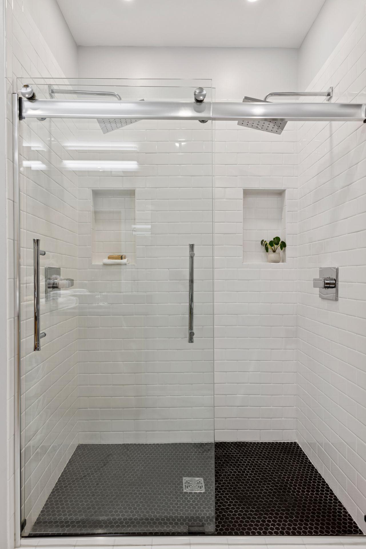 A spa-like tile shower-for-two with glass sliding doors and dual rain faucet heads