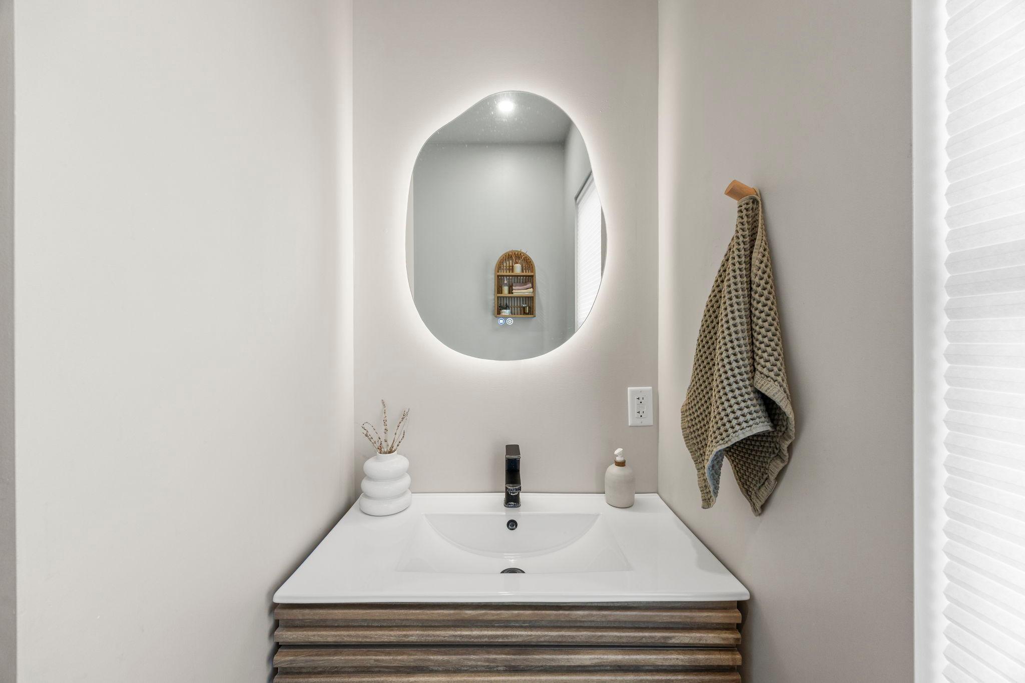 The updated ¾ bathroom, featuring a single vanity with a lighted mirror and a walk-in shower.