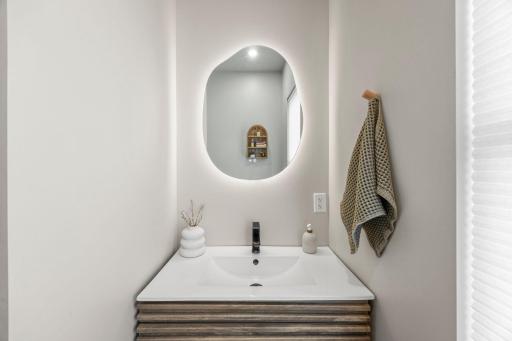 The updated ¾ bathroom, featuring a single vanity with a lighted mirror and a walk-in shower.