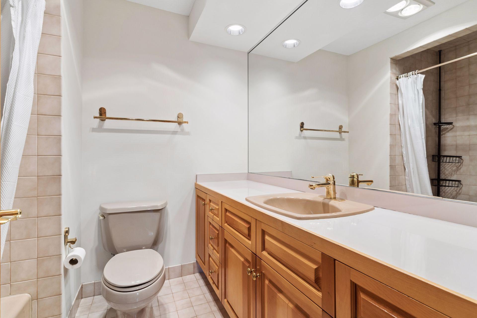 The full lower level bathroom features a tiled bathtub and shower surround.