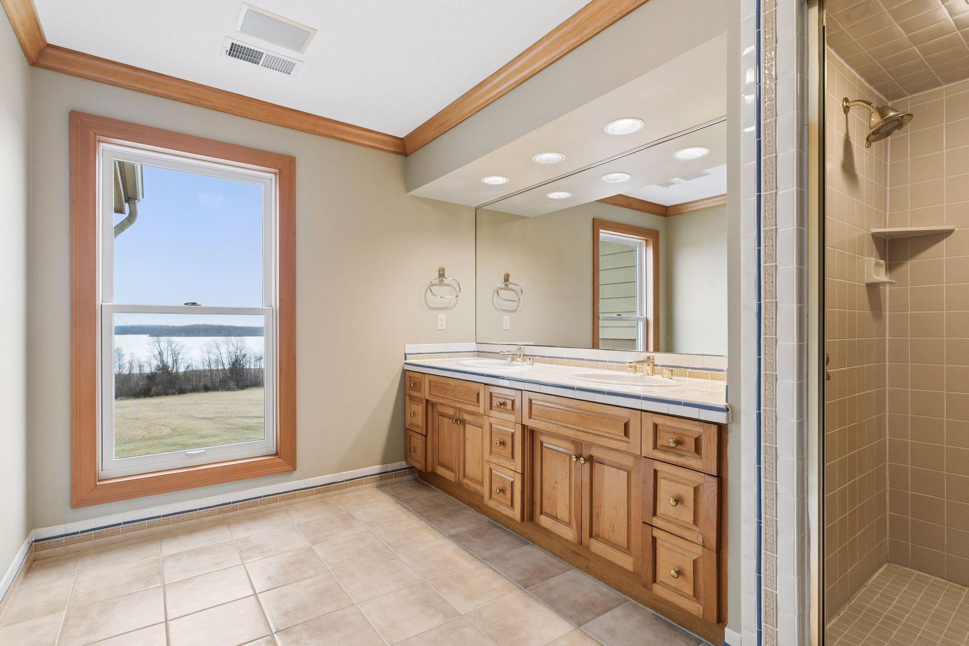 The Primary Suite features crown molding, a vanity with two sinks and a tiled shower.