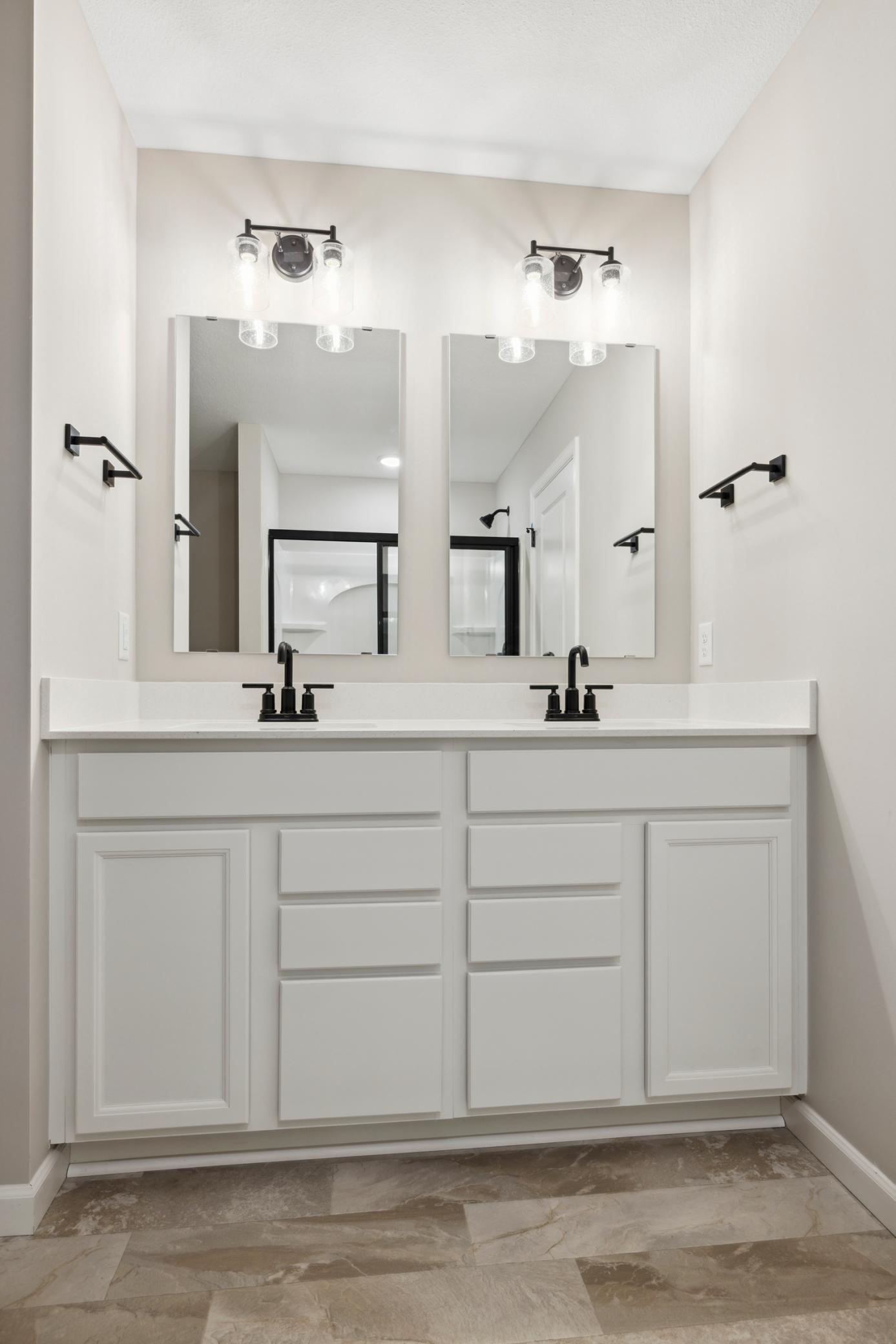 Double vanity with sleek countertops and ample storage provides both function and style