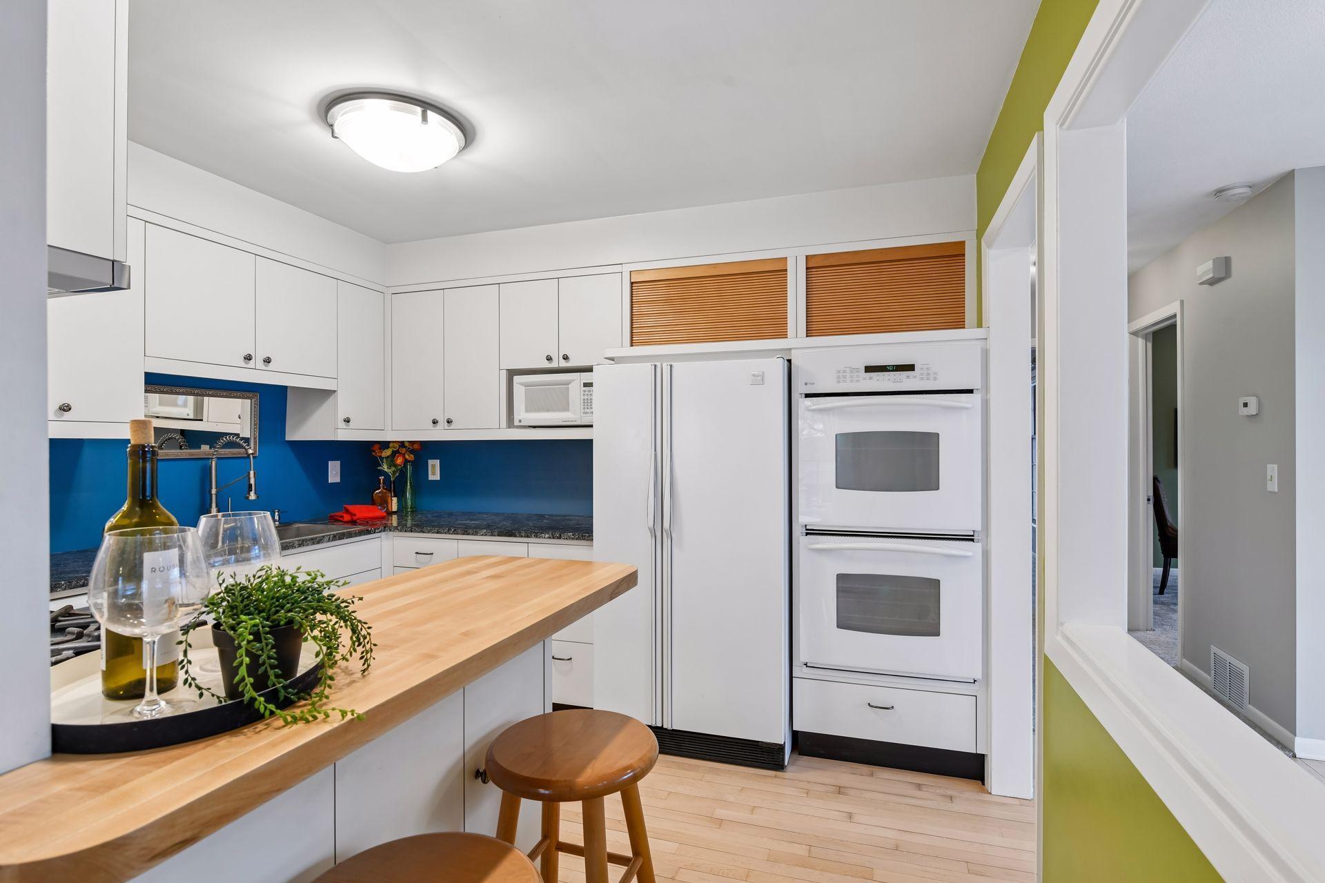 This kitchen has newly refinished hardwood floors, a double oven, gas cooktop with hood fan, Bosch dishwasher and a dedicated microwave shelf.