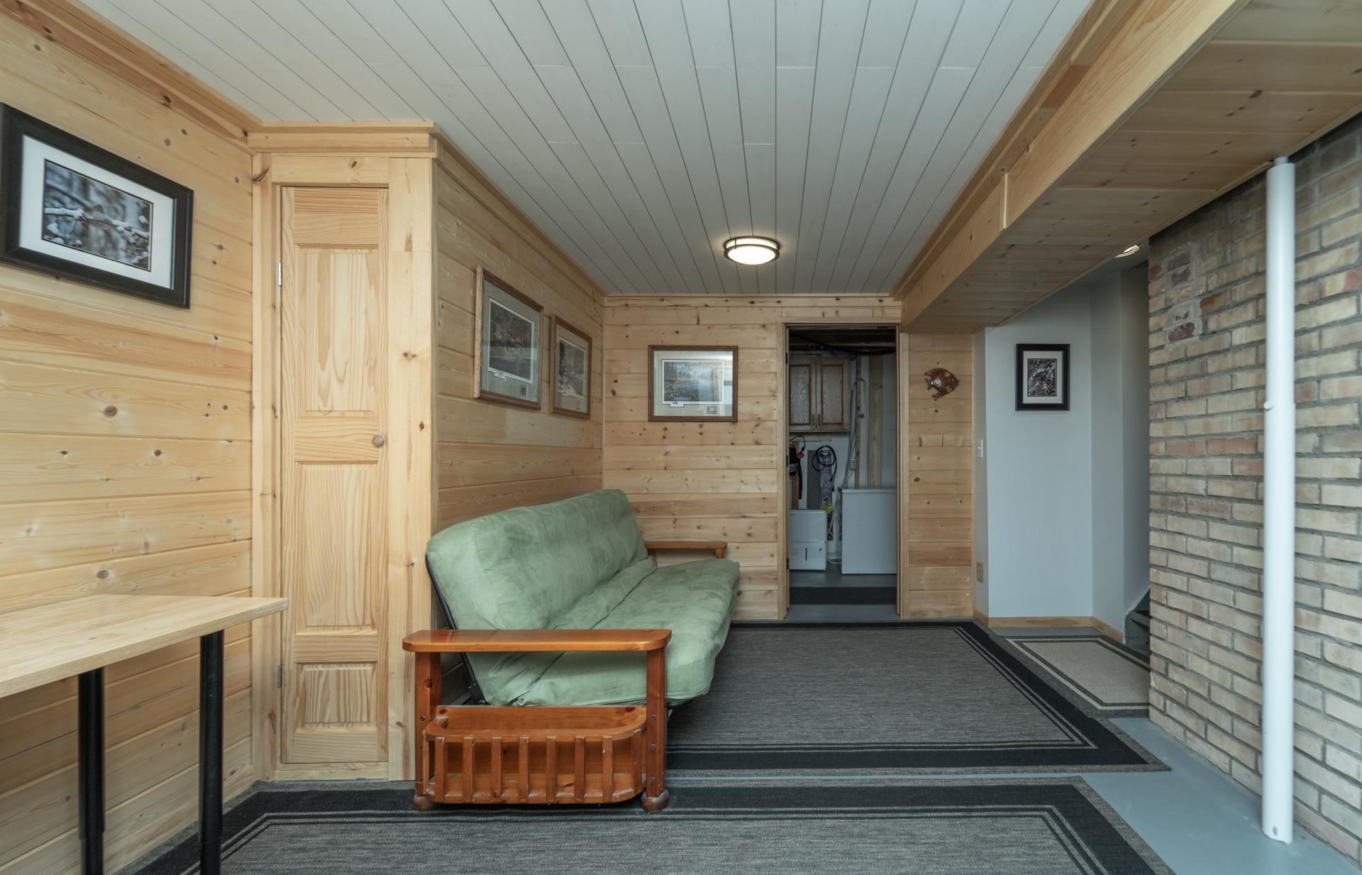 Finished lower level featuring a cozy knotty pine shiplap ceiling.