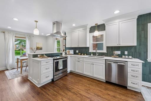 This kitchen blends functionality with modern updates, featuring floor-to-ceiling tile, newer stainless steel appliances, and abundant storage throughout.
