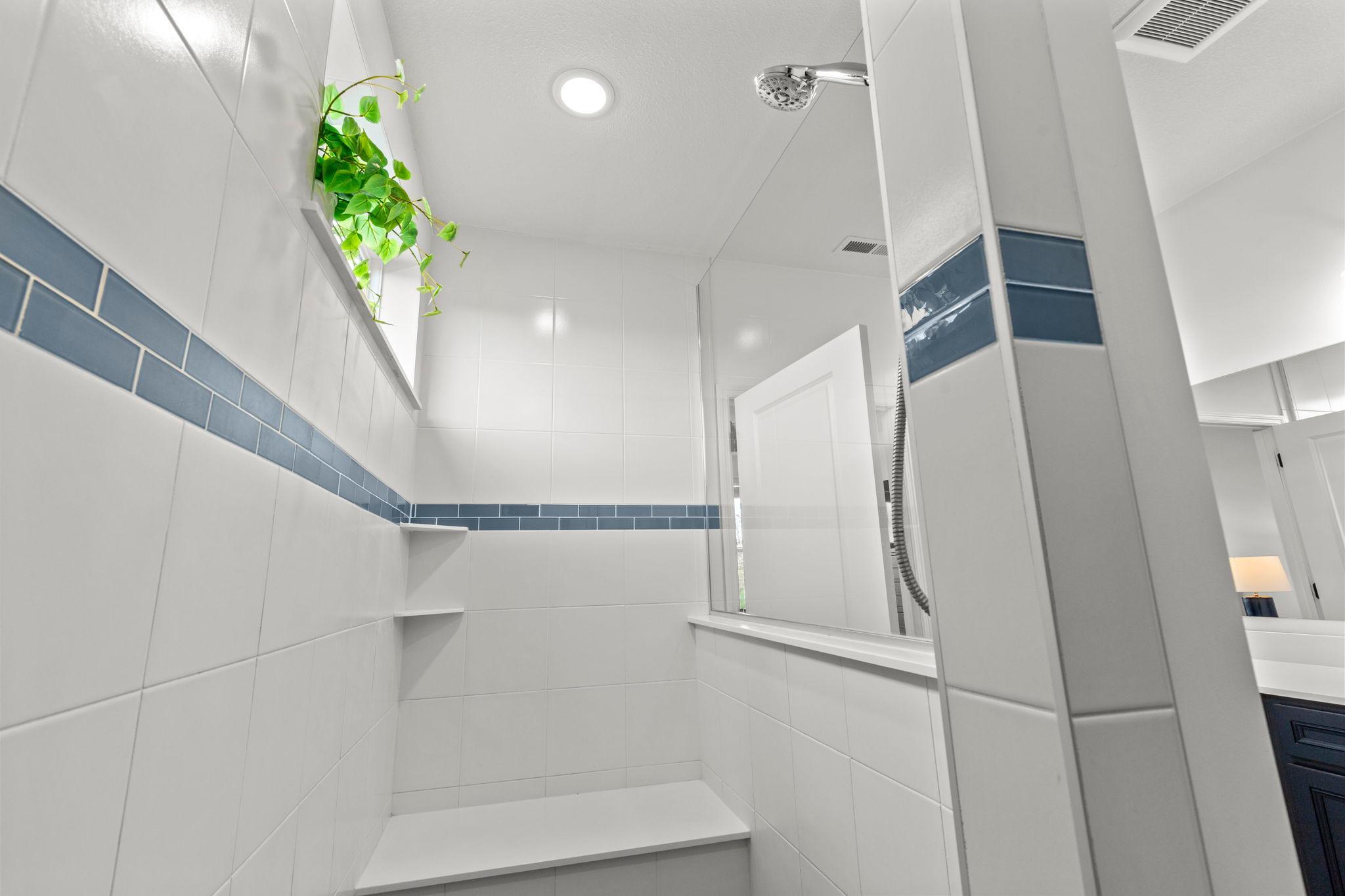 The shower features a built-in bench and window, creating a relaxing spa-like feel