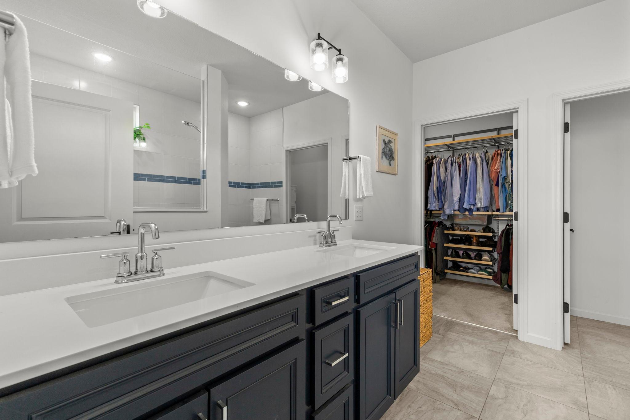 Primary ensuite features double vanity, tile floors, walk-in shower and access to the custom walk-in closet