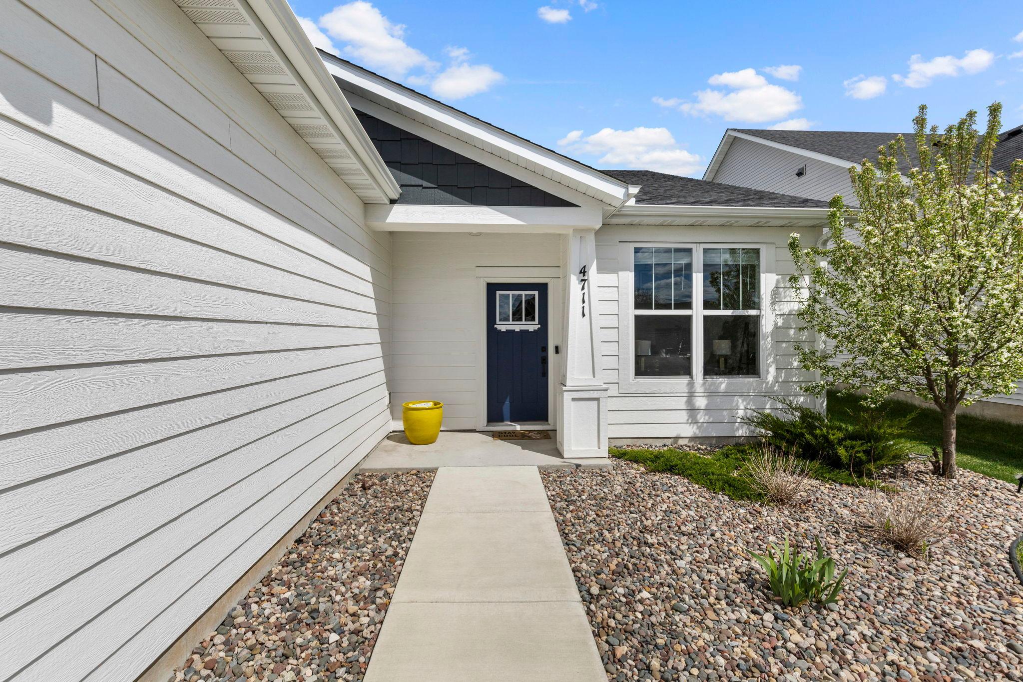 An inviting walkway framed by low-maintenance rock bed landscaping guides you to the front door