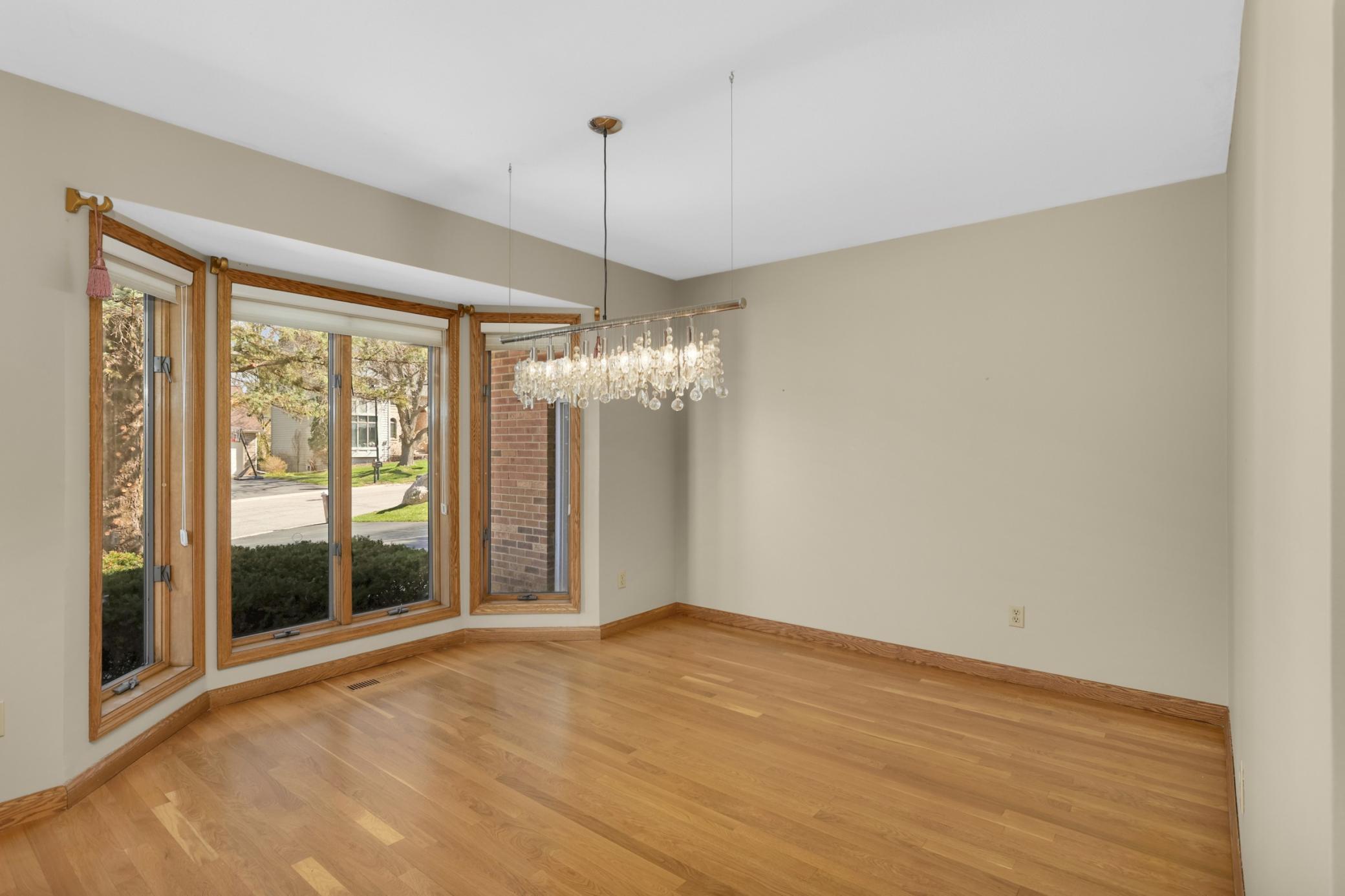 Dining room with lovely wood floors and gorgeous windows overlooking front yard and landscaping.