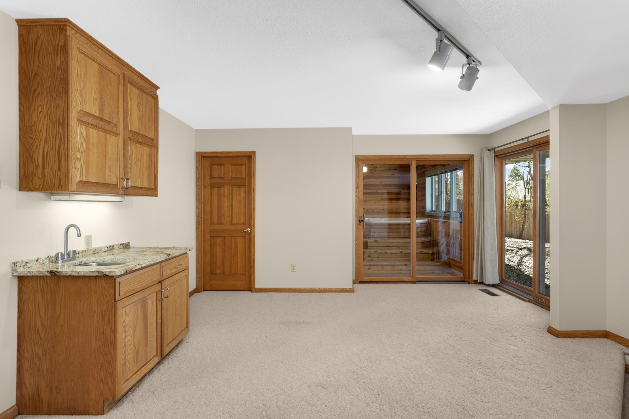 Lower level family room with wet bar and extra storage cabinets, even a hot tub room! If the hot tub is not of interest, this might make a great sauna space if converted.