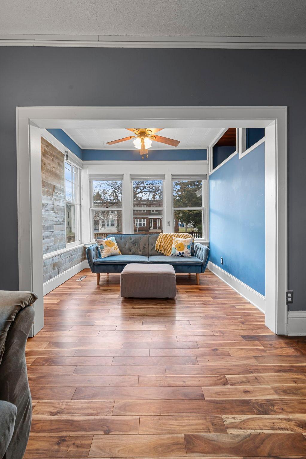 The sunroom showcases a statement wood-paneled accent wall and is filled with natural light.